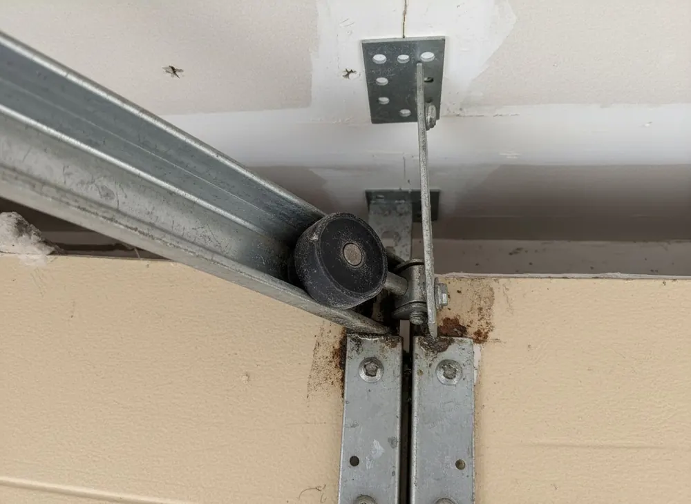 Horizontal garage door track with a worn nylon roller at the curve
